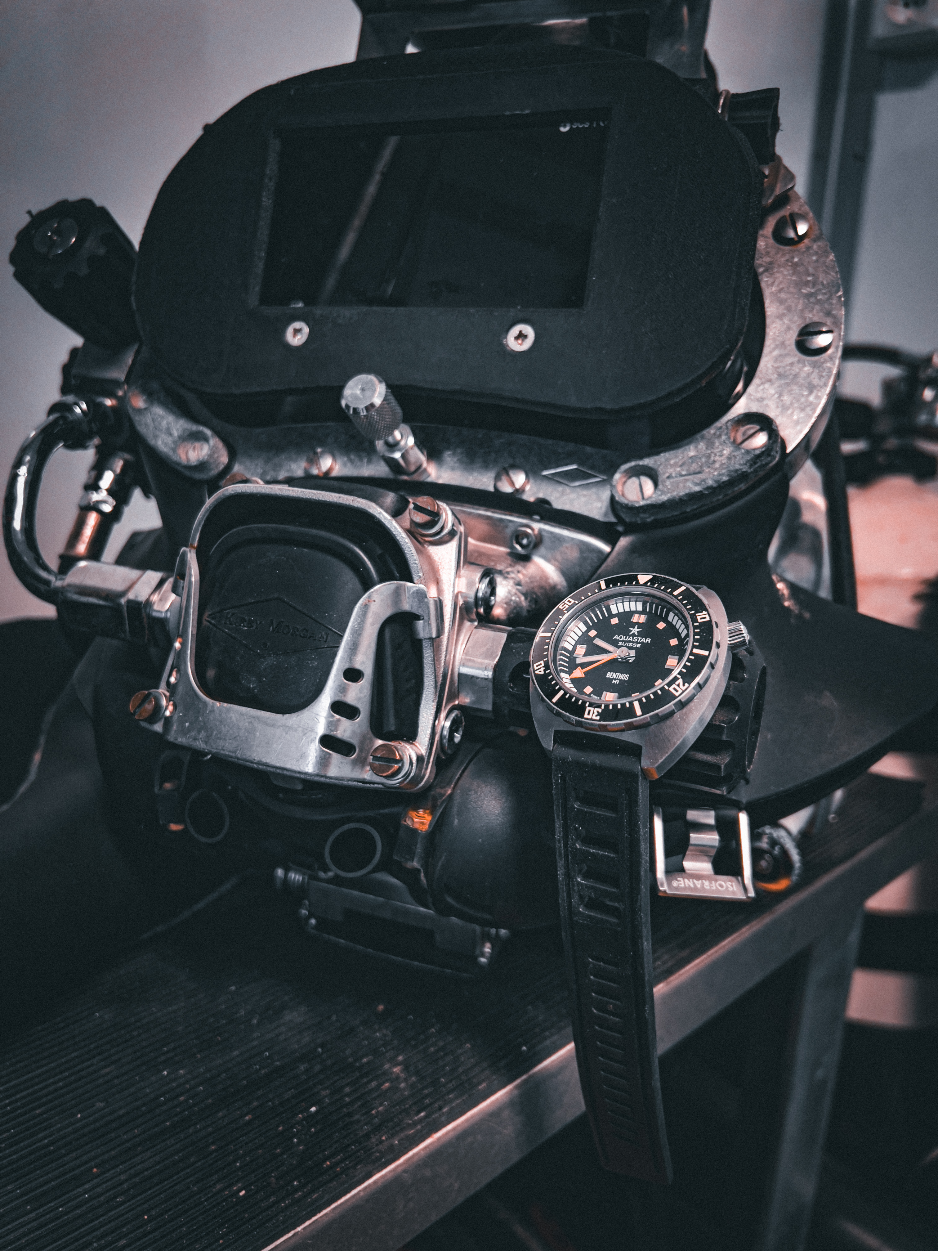 Aquastar Benthos H1 dive watch on a workbench beside a vintage Spirotechnique diving helmet