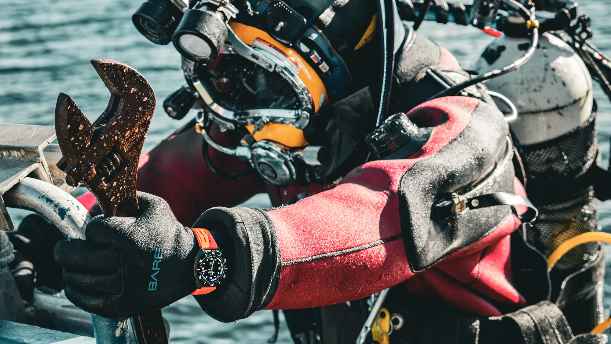 Close view of a commercial diver’s wrist holding a rusty adjustable wrench, an Aquastar Benthos Professional on the dive glove