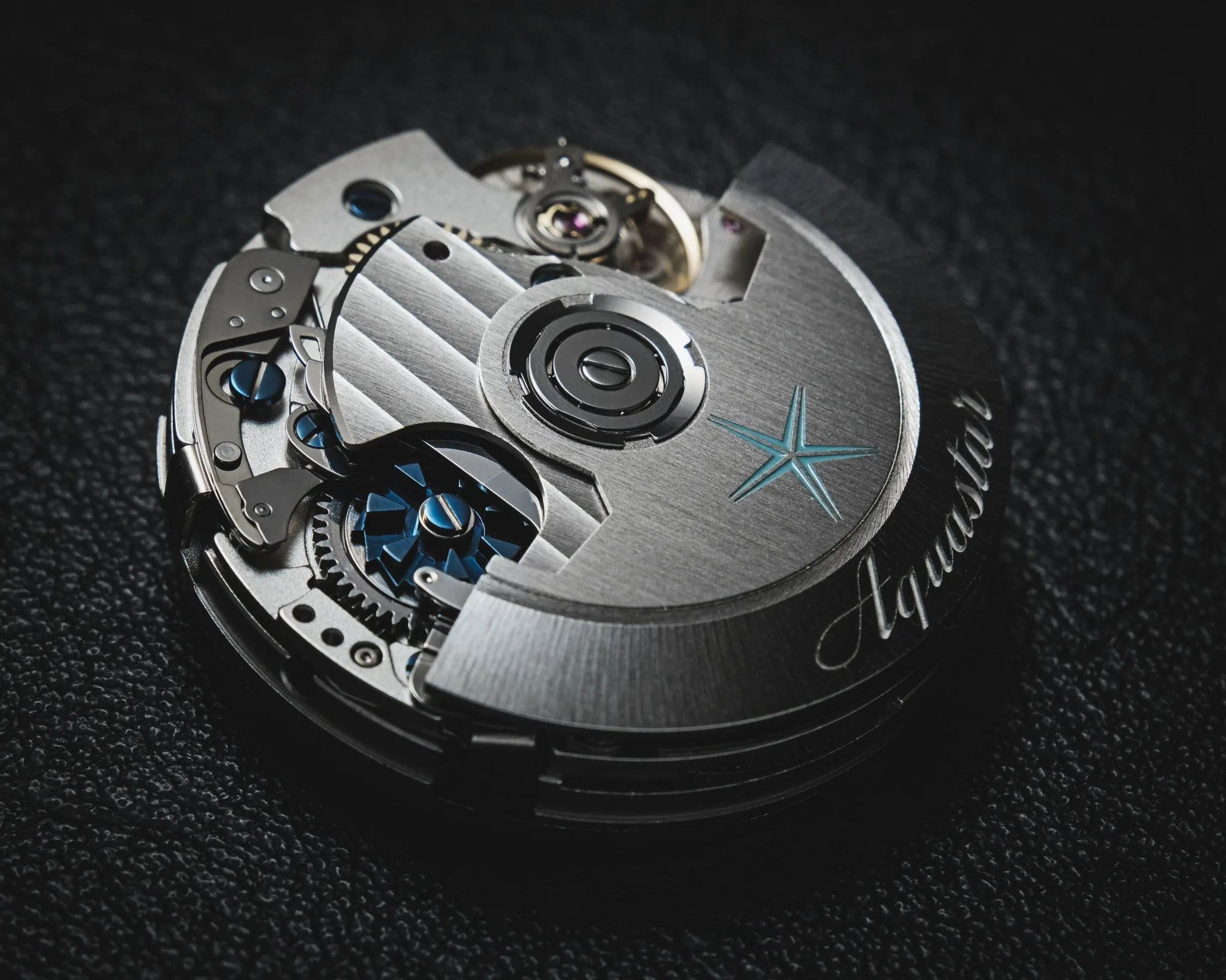 Aquastar Säulenrad-Chronographenwerk in Dreiviertelansicht, der gebürstete Rotor mit Aquastar-Gravur, das blaue Säulenrad und die Unruh sichtbar in der offenen Werkarchitektur