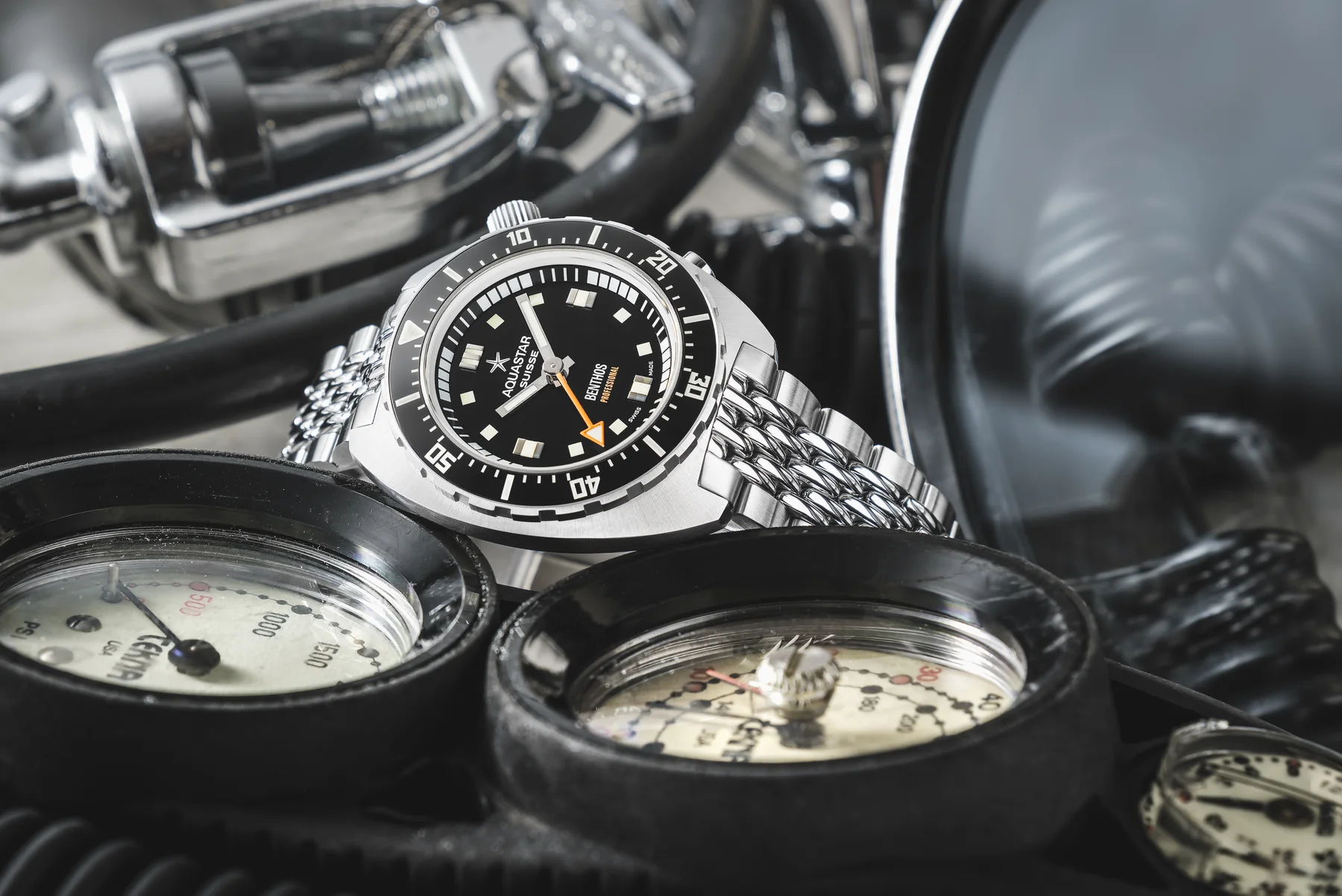 An Aquastar Benthos Professional on a steel bracelet among diving gauges and regulators